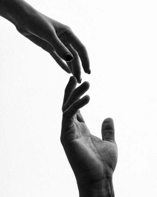 Two hands reaching out, captured in black and white style, symbolizing connection.